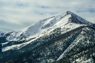 航空摄影的山脉被雪覆盖在多云的天空下
